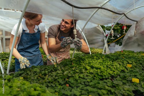 Two gardeners smiling in a greenhouse