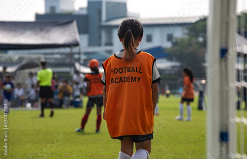 Young girl soccer goalkeeper looking at her team making an attack during the match. Youth U11 Soccer game on a sunny summer school tournament day. Football match going on in a background.	