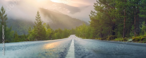 Scenic mountain road through lush forest with misty mountain range in the background  captured during sunrise. Tranquil and picturesque view.