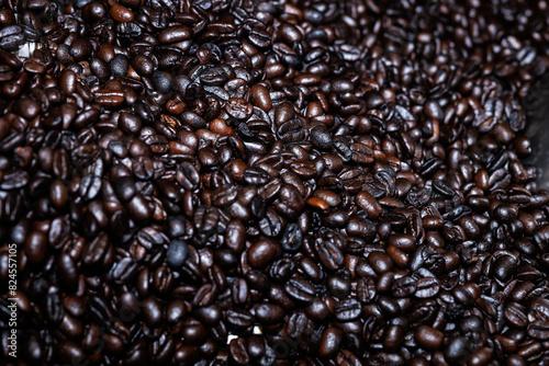 Close up of roasted coffee beans surface rotate in a spinning roaster mashine for background