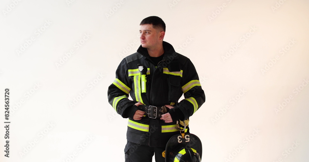 Portrait of strong serious firefighter in uniform standing on white background in studio and looking at camera. Concept of saving lives, heroic profession, fire safety Portrait of strong serious firefighter in uniform standing on white background in studio and looking at camera. Concept of saving lives, heroic profession, fire safety