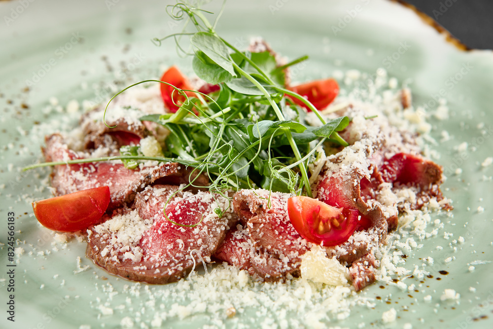 Roast beef carpaccio with Parmesan, arugula, and tomatoes on a speckled turquoise plate Roast beef carpaccio with Parmesan, arugula, and tomatoes on a speckled turquoise plate
