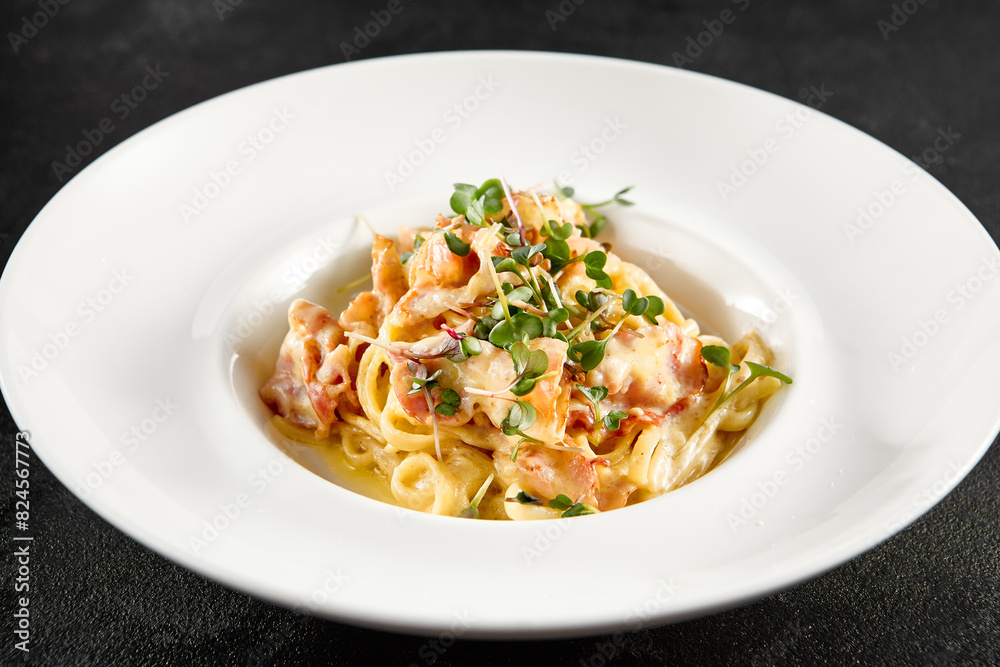 Classic carbonara pasta with a creamy sauce and garnished with fresh herbs, presented on a white plate