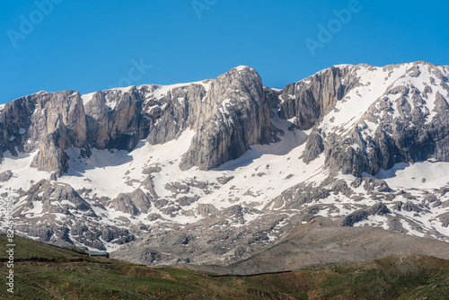 The lush green Sobucimen plateau in spring and the mountains with some melted snow behind. photo