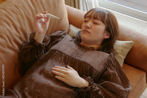 体調不良で体温を計っている女性 photo
