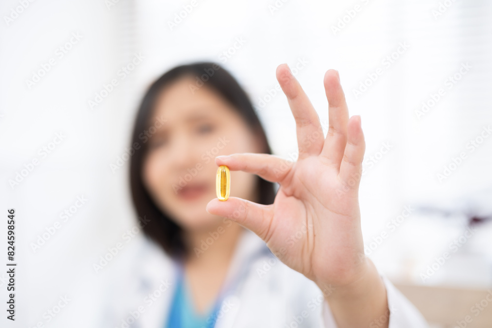 Healthcare worker holding a vitamin, tablets and medical equipment on desk .Doctor in a clinical setting, holding a capsule and smiling . Healthcare worker holding a vitamin, tablets and medical equipment on desk .Doctor in a clinical setting, holding a capsule and smiling .