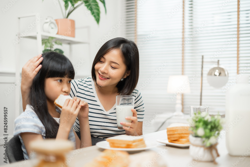 Parents and daughter enjoying breakfast with milk in a warm, inviting kitchen.Asian family breakfast scene, parents and daughter eating and drinking milk at home Parents and daughter enjoying breakfast with milk in a warm, inviting kitchen.Asian family breakfast scene, parents and daughter eating and drinking milk at home