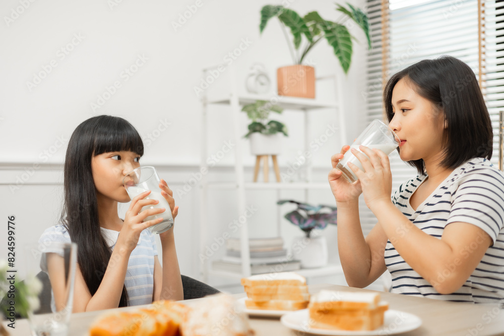 Parents and daughter enjoying breakfast with milk in a warm, inviting kitchen.Asian family breakfast scene, parents and daughter eating and drinking milk at home Parents and daughter enjoying breakfast with milk in a warm, inviting kitchen.Asian family breakfast scene, parents and daughter eating and drinking milk at home