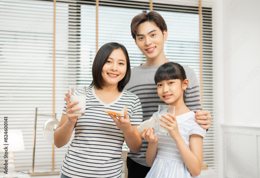 Parents and daughter enjoying breakfast with milk in a warm, inviting kitchen.Asian family breakfast scene, parents and daughter eating and drinking milk at home Parents and daughter enjoying breakfast with milk in a warm, inviting kitchen.Asian family breakfast scene, parents and daughter eating and drinking milk at home