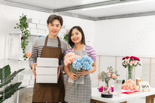 A couple of Asian entrepreneurs using their smartphones to sell flowers online.