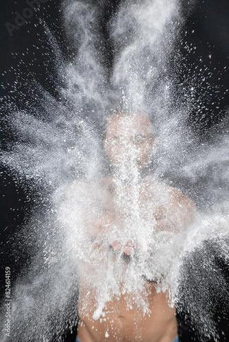 Fotografie Strong shirtless man patting flour into his hands creating explosion