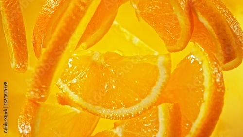 Freeze Motion of Flying Orange Slices into Water, Colored Background.