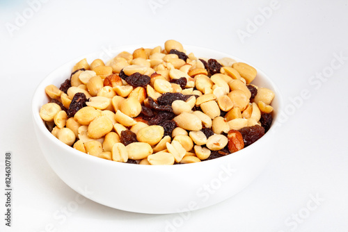 Peanut and raisin mix in round white bowl, isolated on white