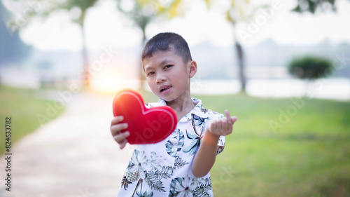 happy little boy holding a red heart-shaped toy on valentine's day