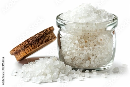 A jar of coarse sea salt with a wooden lid next to it on a white background. Perfect for cooking, seasoning, and culinary uses.