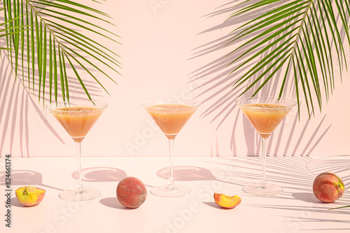 Peach juice and fruit with palm leaves on a pink background. Summer refresing drink concept. photo