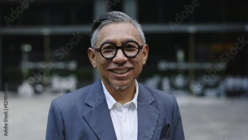 Wallpaper Mural Mature Handsome Smiling Asian Man in Glasses and Formal Suit Looking at Camera. Portrait of a Nicely Dressed Businessman Standing, Posing in the Street. Business and People Concept Torontodigital.ca