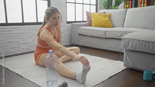 A young woman stretching on a yoga mat in a modern living room photo