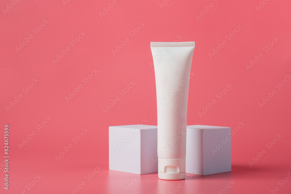 Plastic white tube for cream or lotion. Skin care or sunscreen cosmetic with stylish props on pink background. Plastic white tube for cream or lotion. Skin care or sunscreen cosmetic with stylish props on pink background.