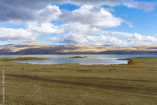 Curved shores of Lake Paravani in front of mountains covered with clouds