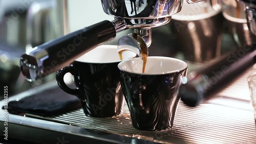 Close-up of the Espresso coffee extraction from a professional coffee machine with a bottomless filter. Coffee flowing into cup. Coffee aroma and the warm shop atmosphere photo