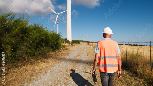 Engineer Walking Under Wind Turbines 