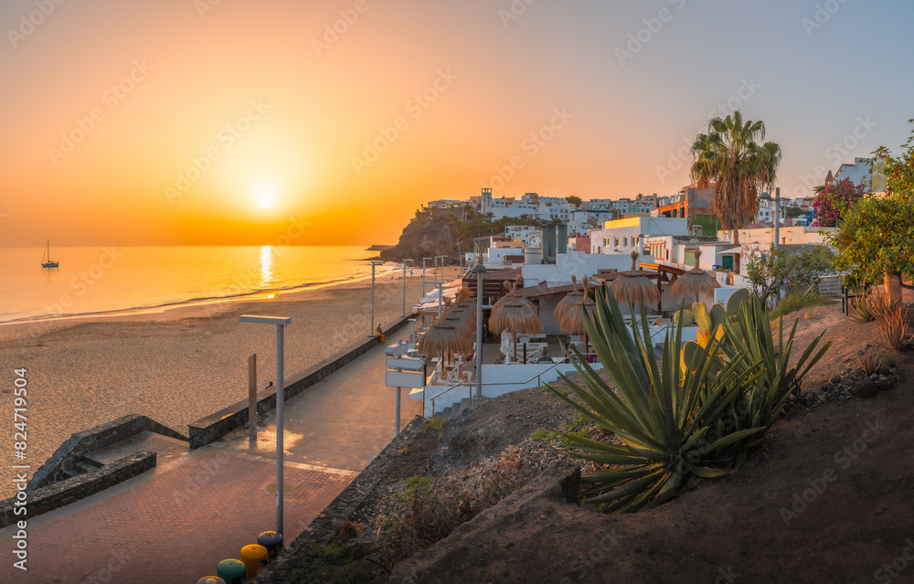 Bask in the warm glow of sunset at Morro Jable, Fuerteventura, where golden sands meet tranquil Atlantic waters