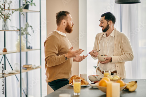 Two happy gay men chatting in a modern kitchen  discussing breakfast options and enjoying each others company.