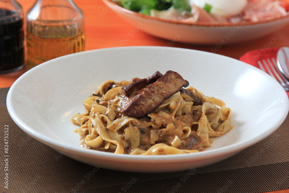 Grilled Foie gras steak with with Fettuccine pasta on restaurant table Grilled Foie gras steak with with Fettuccine pasta on restaurant table