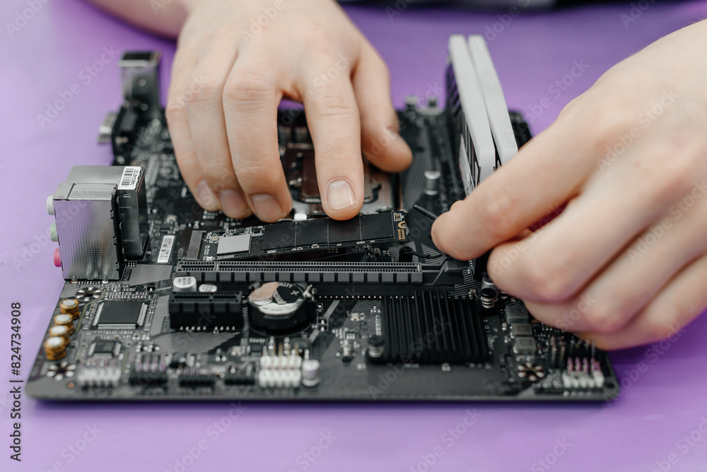 system administrator installing SSD into motherboard, assembling PC of different accessories or components, close-up view of hands, computer repair and maintenance concept system administrator installing SSD into motherboard, assembling PC of different accessories or components, close-up view of hands, computer repair and maintenance concept