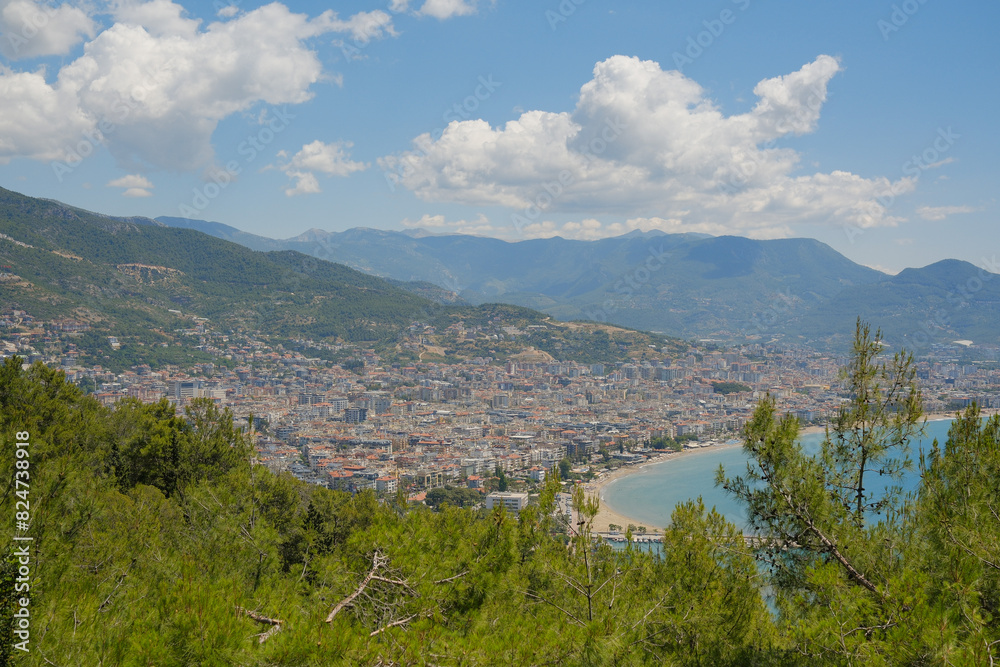 Concept of rest. Sea surface with clouds on horizon and costline town with mountains on the background.