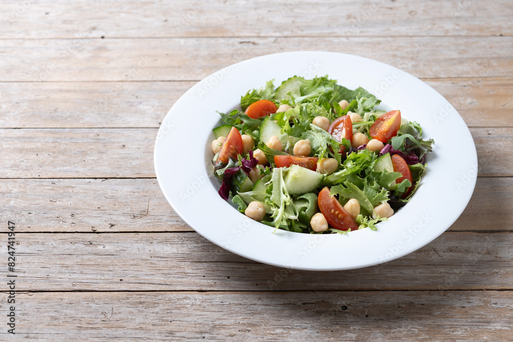 Healthy chickpea salad with tomato,lettuce and cucumber on wooden table. Copy space Healthy chickpea salad with tomato,lettuce and cucumber on wooden table. Copy space
