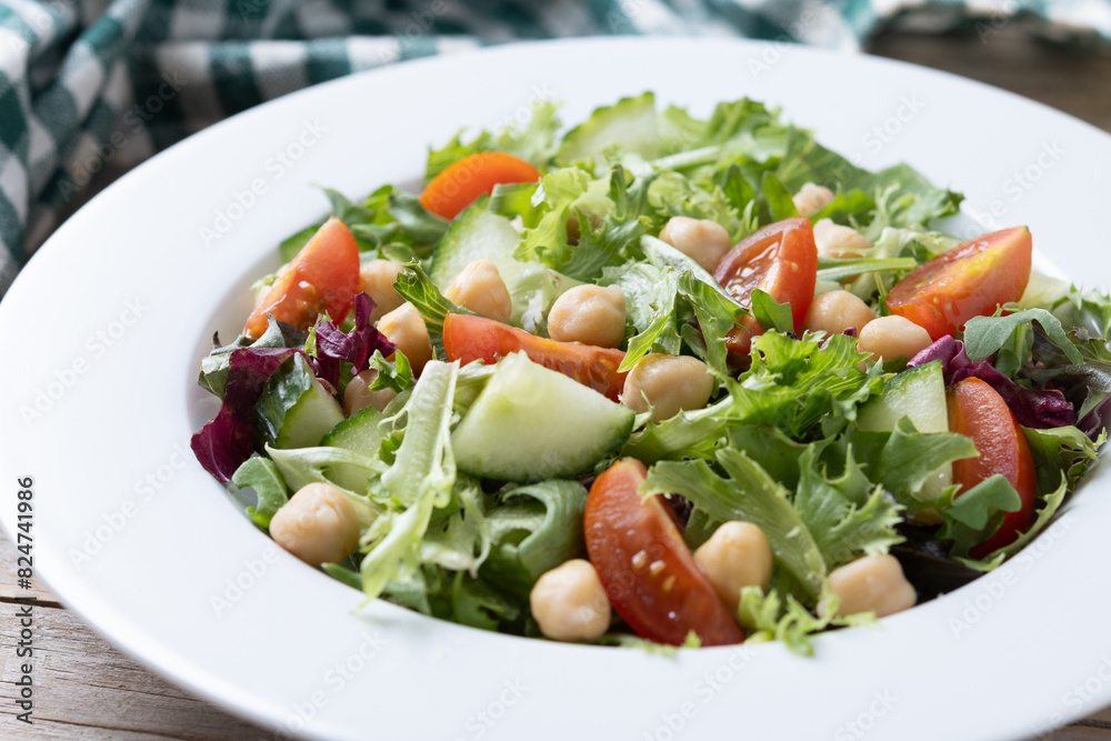 Healthy chickpea salad with tomato,lettuce and cucumber on wooden table. Close up