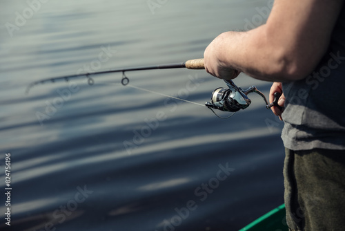 Freshwater fishing in summer. A fisherman using a spinning with a spinning reel to catch predatory freshwater fish.