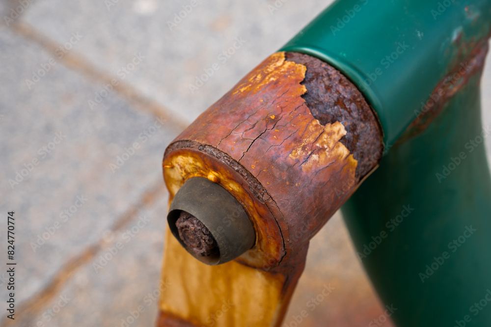 A green bench with a rusted bolt on the back. The bolt is missing and the bench is in need of repair A green bench with a rusted bolt on the back. The bolt is missing and the bench is in need of repair