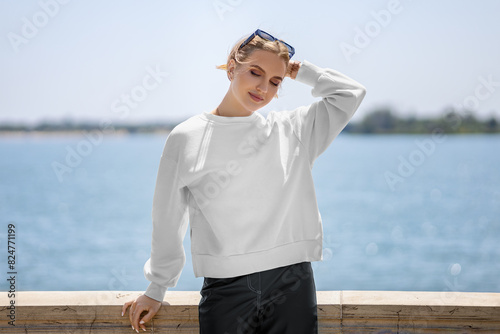 Mockup of a white sweatshirt on a girl with glasses, on the background of the river, clothes with long sleeves, front view.