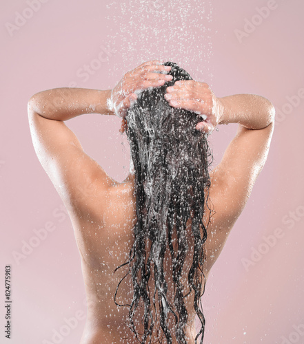 Woman, hair and shower or back in studio, pink background and relaxing for cleaning or model with water. Grooming, hygiene and female person wet for self care, showering and wellness routine