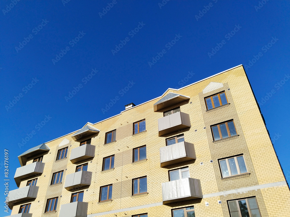Facade of new multi-story residential building. Sale and rental apartments. Housing development. Cityscape. City life. Real estate. Blue sky. Mortgage concept. Condos. Interest Rate Increase. Flat. Facade of new multi-story residential building. Sale and rental apartments. Housing development. Cityscape. City life. Real estate. Blue sky. Mortgage concept. Condos. Interest Rate Increase. Flat.