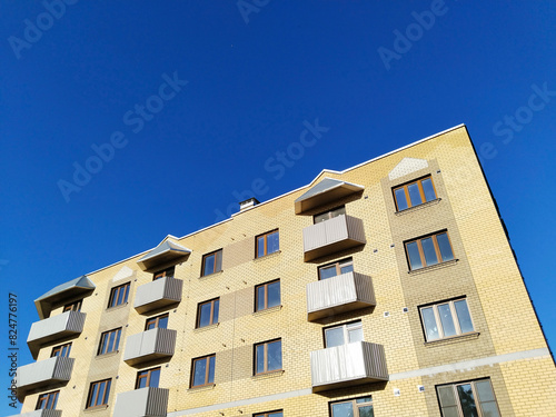 Facade of new multi-story residential building. Sale and rental apartments. Housing development. Cityscape. City life. Real estate. Blue sky. Mortgage concept. Condos. Interest Rate Increase. Flat. photo