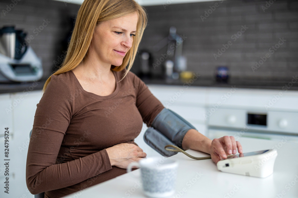 Pregnant woman measuring her blood pressure at home
