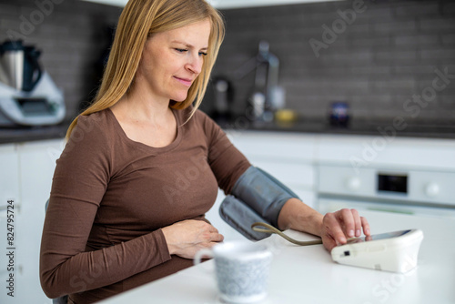 Pregnant woman measuring her blood pressure at home 