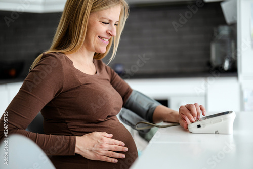 Pregnant woman measuring her blood pressure at home
