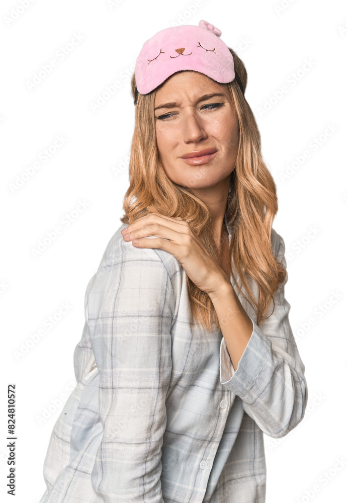 Blonde in pajamas with sleep mask having a shoulder pain. Blonde in pajamas with sleep mask having a shoulder pain.