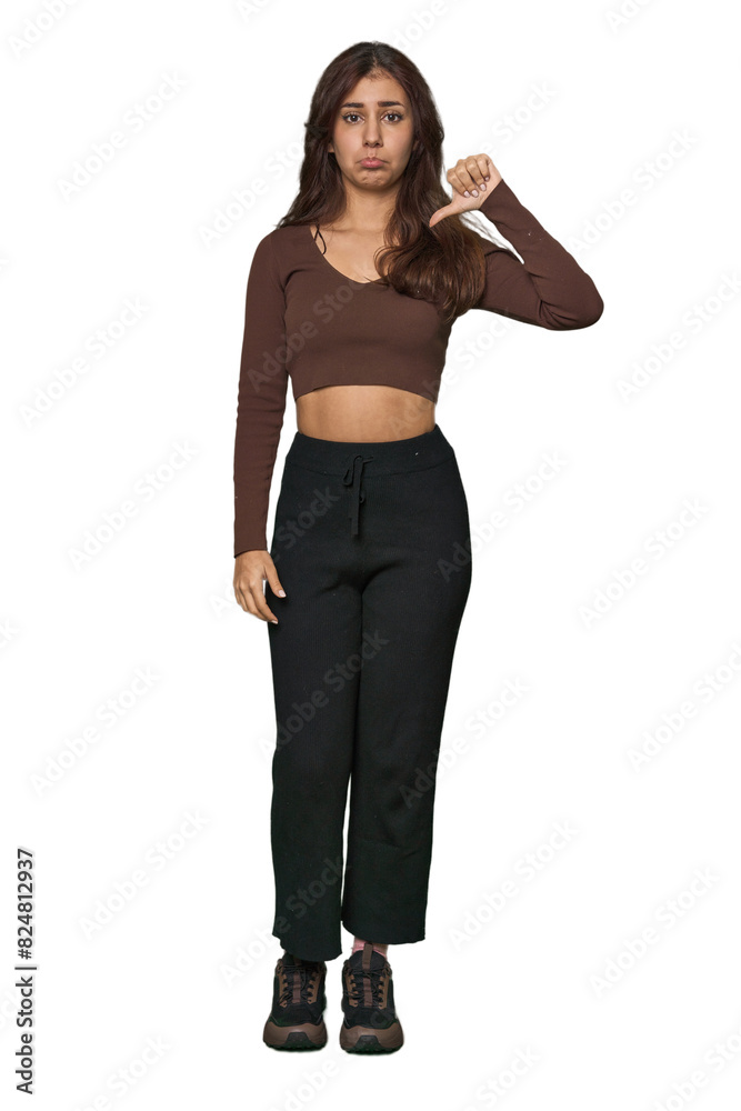 Middle Eastern woman, full body studio showing a dislike gesture, thumbs down. Disagreement concept. Middle Eastern woman, full body studio showing a dislike gesture, thumbs down. Disagreement concept.