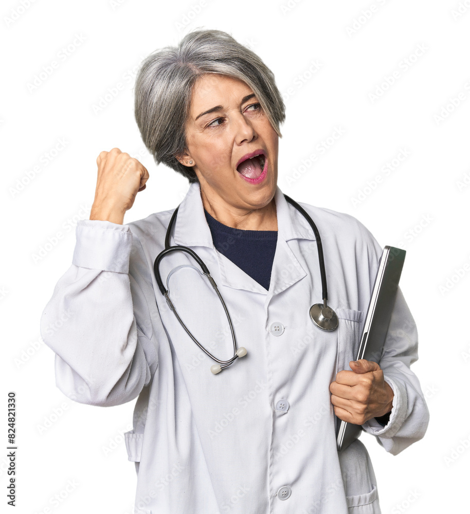 Caucasian mid-age doctor holding laptop raising fist after a victory, winner concept. Caucasian mid-age doctor holding laptop raising fist after a victory, winner concept.