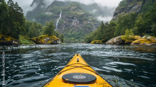 Perspective from inside a kayak navigating a river surrounded by foggy mountains photo