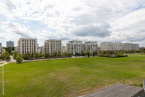 Moderne Wohnanlage mit weißen Mehrfamilienhäusern an einer weitläufigen Grünfläche in einem zeitgemäßen Stadtquartier
