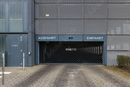 Moderne Parkhausfassade mit markierter Ein- und Ausfahrt sowie einem geschlossenen Gitterrolltor