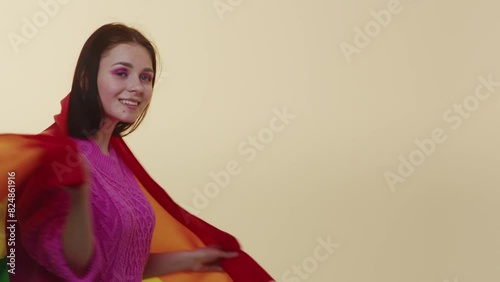 An adult protest woman showing multicolor LGBT flag, as symbol of freedom. Stop gender discrimination. Be tolerance. A young girl raising hands up with rainbow flag isolated on beige color background photo