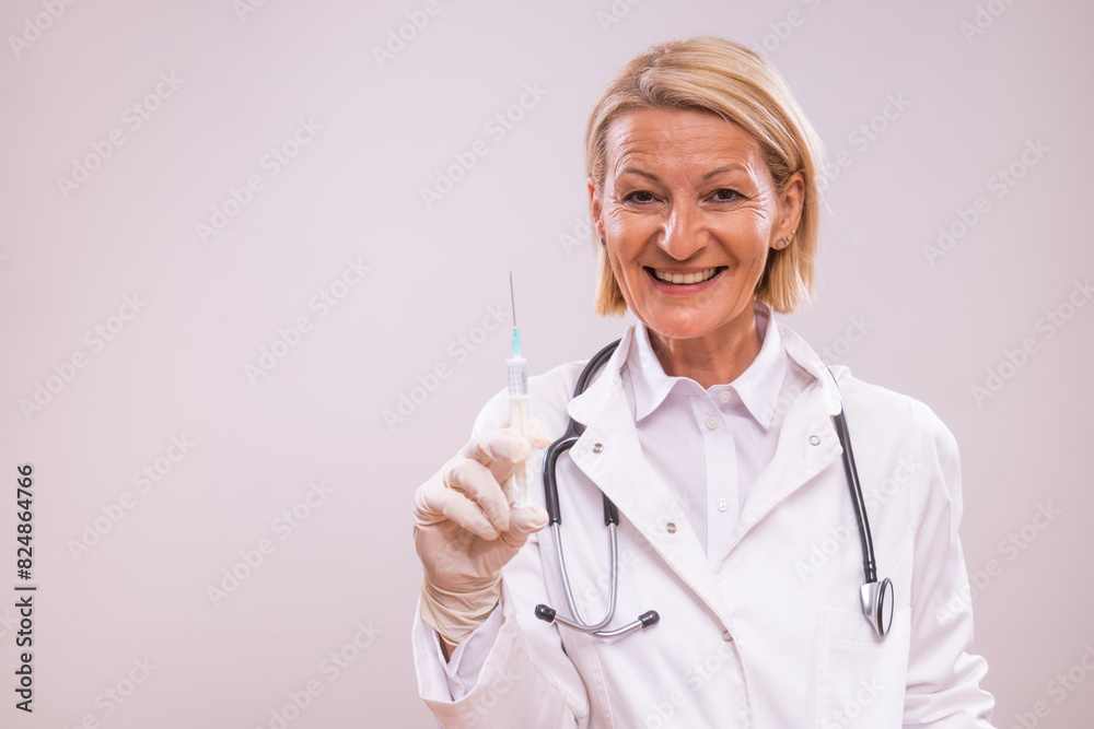 Portrait of mature female doctor with injection on gray background. Portrait of mature female doctor with injection on gray background.